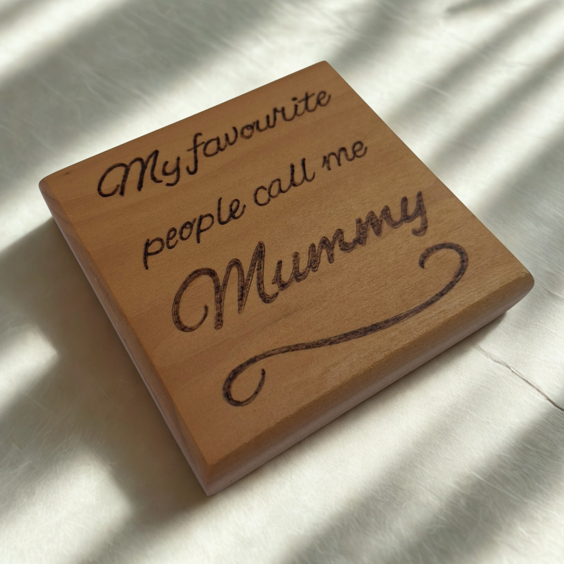 Wooden block with engraved text 'My favourite people call me Mummy' on a light background