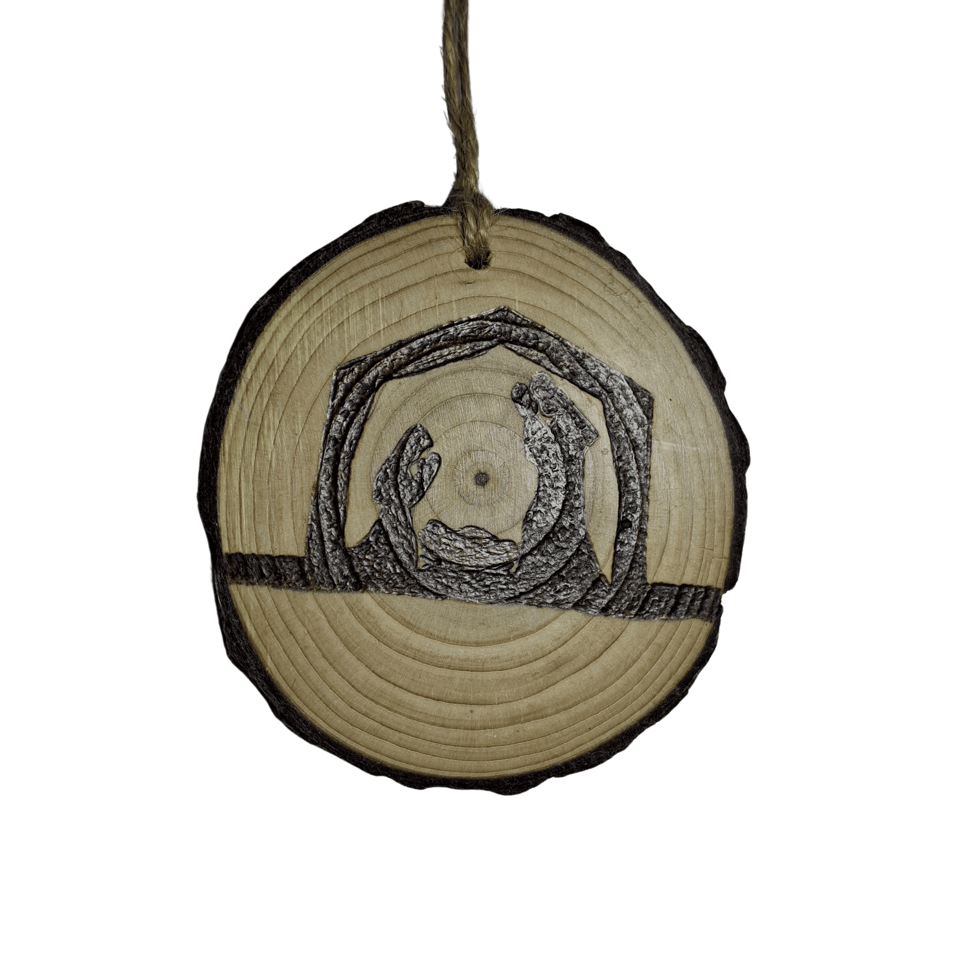 A small Christmas ornament, a wooden log slice with a jute rope for hanging, is shown on a black background. The ornament is decorated with a pyrography design of a nativity scene featuring Mary, Joseph, and baby Jesus in a manger.