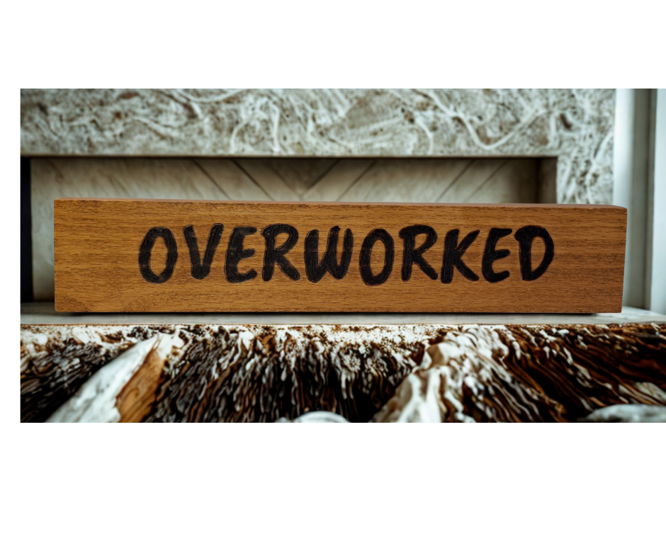 A hand-burnt, freestanding wooden plaque with the word "Overworked" in a casual, handwritten style. The wood has visible grain and a rustic, natural finish.