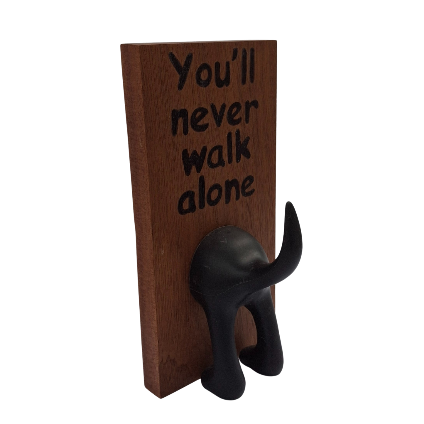 Wooden plaque with black text 'You'll never walk alone' and a black dog-shaped hook on a white background.