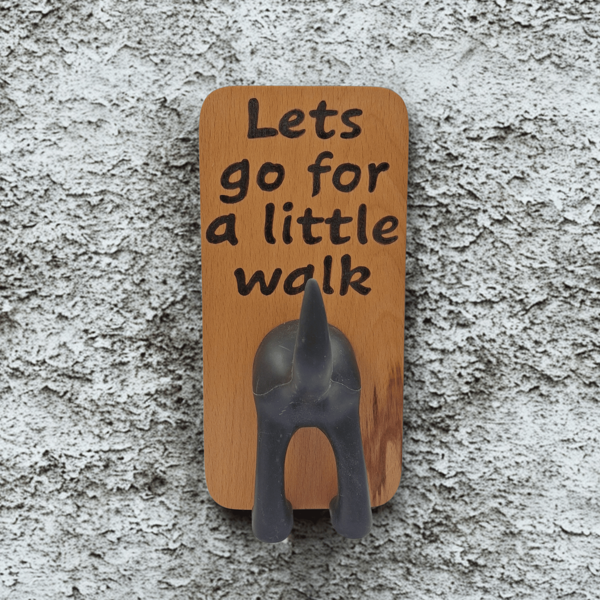 Wooden wall hook featuring the phrase "Lets go for a little walk" created with pyrography (hand burnt lettering). A black dog's rear end forms the hook. 