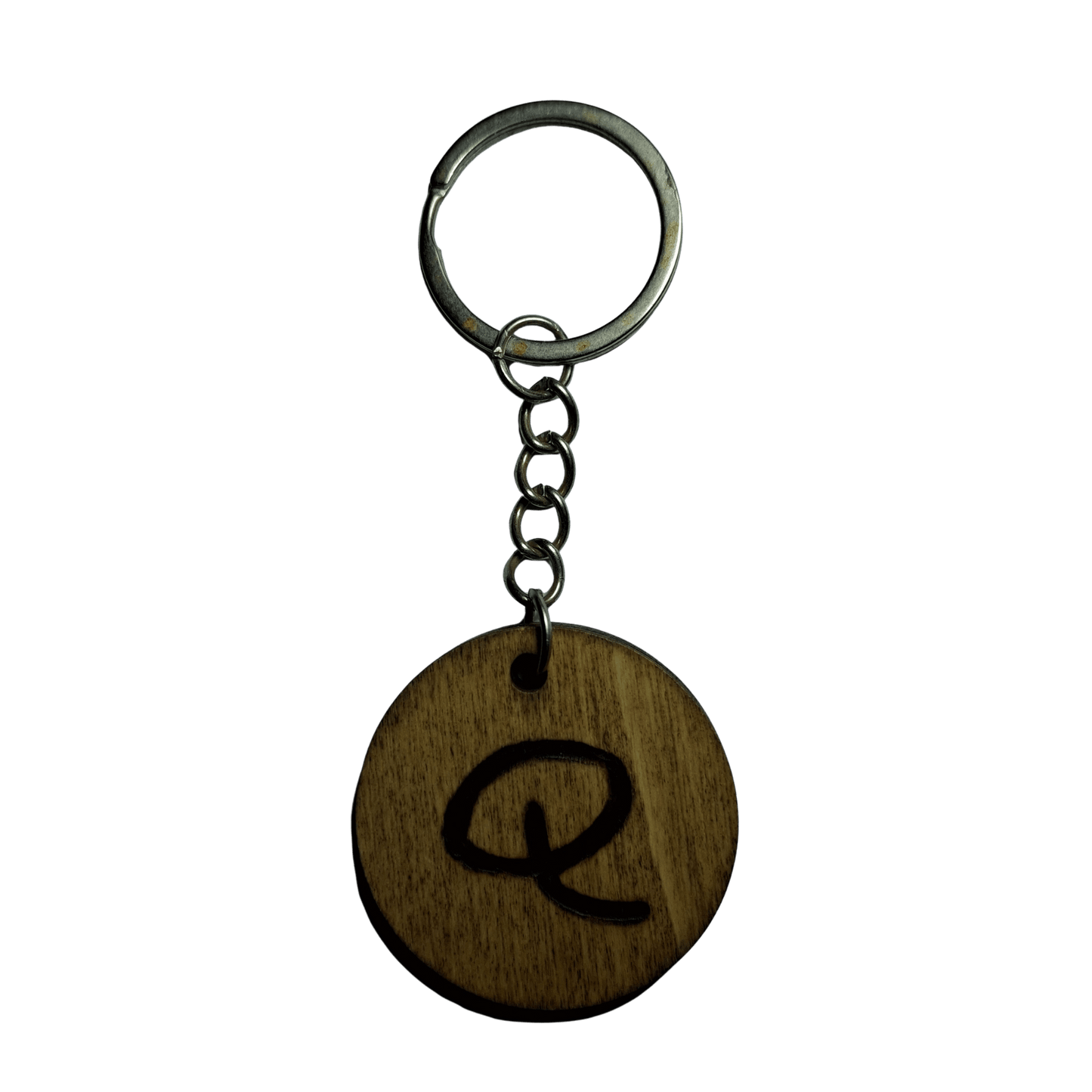 Round keyring made from veneered plywood. The letter Q is hand-burnt using pyrography, finished with a hardwax oil, and attached to a silver keychain.