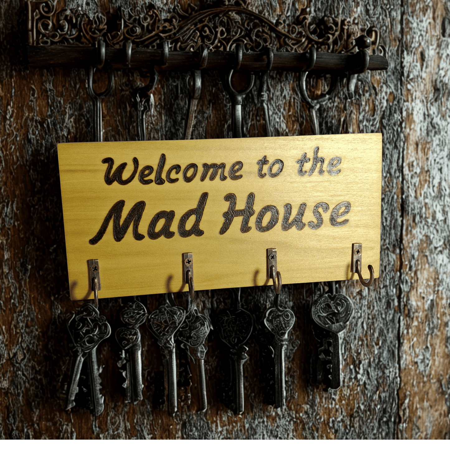 Key holder with 'Welcome to the Mad House' sign on a wooden background