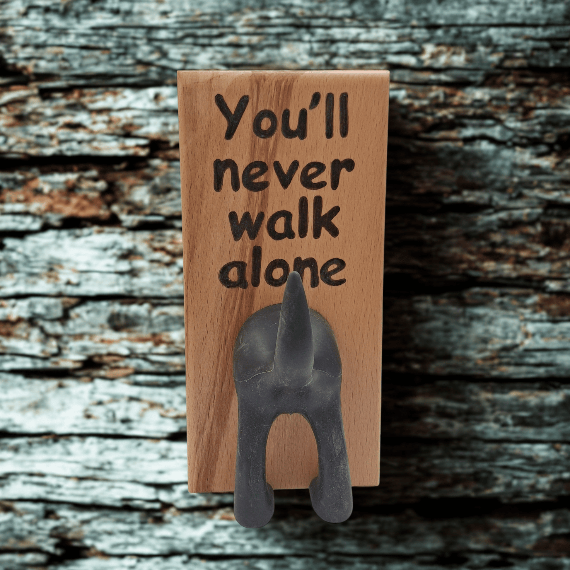 Wooden wall hook featuring the phrase "You'll never walk alone" created with pyrography (hand burnt lettering). A black dog's rear end forms the hook. 